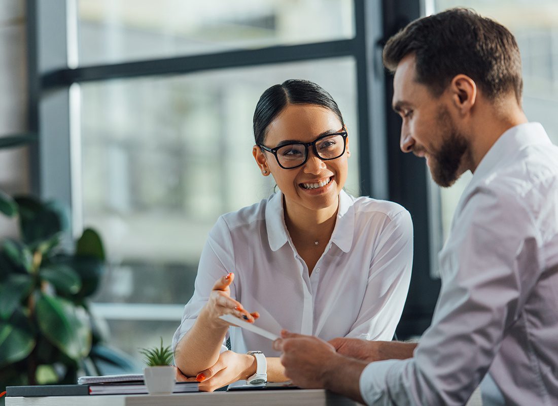 Contact - Happy Agent With Glasses Reviews Information With Her Client at an Office